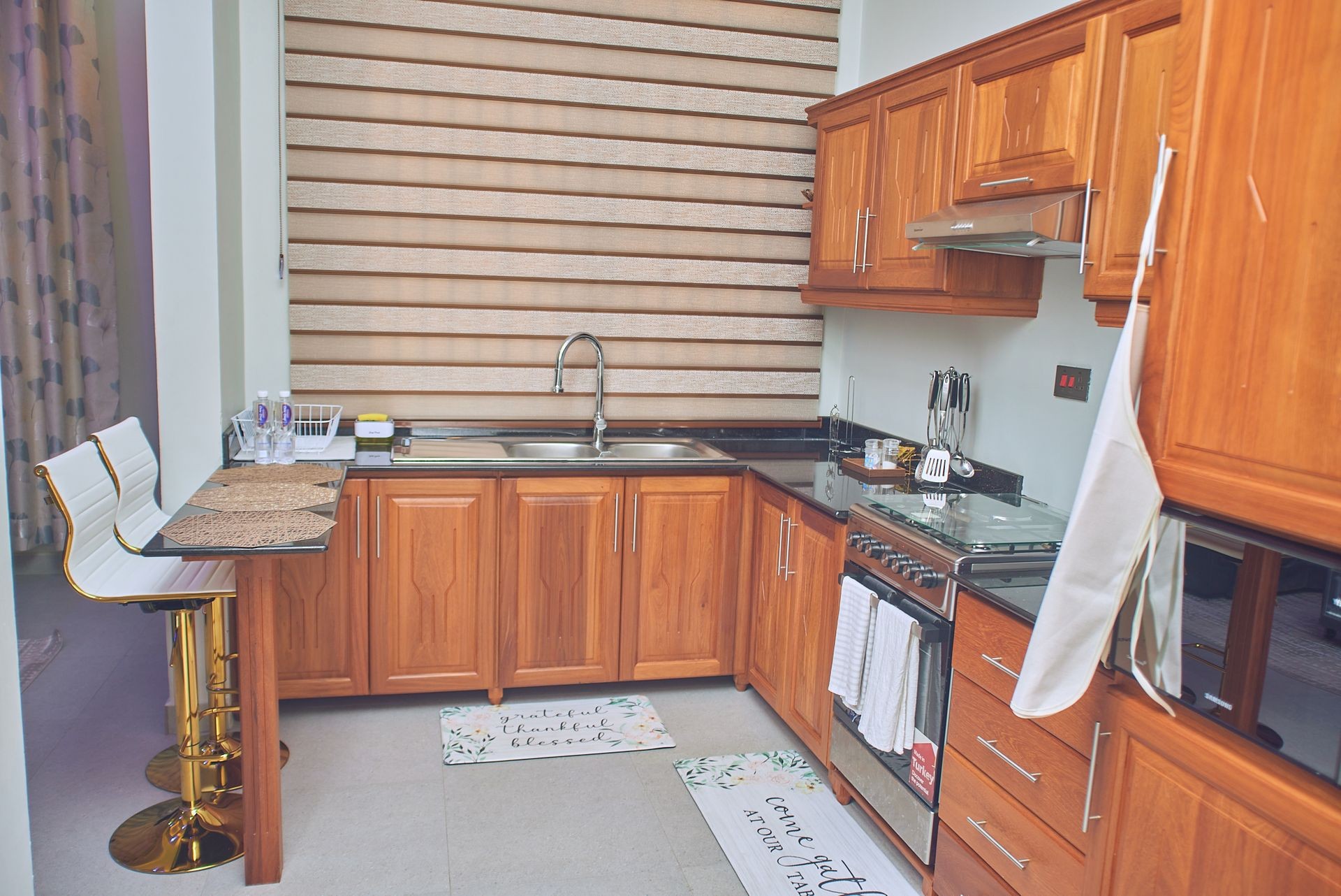 Modern kitchen with wooden cabinets, countertop, bar stools, and a stainless steel stove.