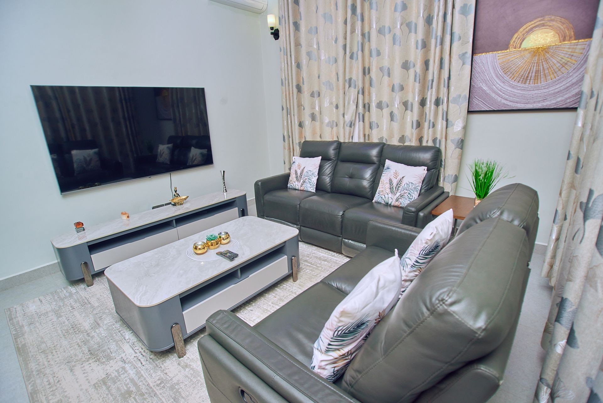 Modern living room with gray sofas, a wall-mounted TV, and a stylish coffee table.